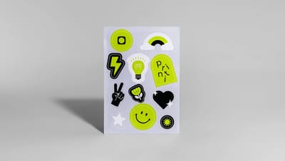 Detalhe de cartela de adesivos personalizados da Printi com a frase "A sua gráfica, sempre" e ícones coloridos em alta resolução.