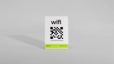 Display em L de mesa feito de papel resistente com impressão de QR Code para Wi-Fi, visto de frente em fundo cinza neutro.