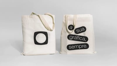 Par de ecobags de algodão cru personalizadas exibindo frente com logotipo e verso com frase institucional, ideal para eventos e ações de marketing.