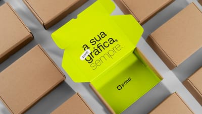 Caixa de papelão para transporte aberta exibindo impressão interna personalizada em verde neon com a frase "A sua gráfica, sempre" da Printi.