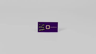 Cartão de visita roxo com acabamento em hot stamping dourado, com a frase “a sua gráfica, sempre” e logotipo Printi, posicionado sobre fundo cinza claro.