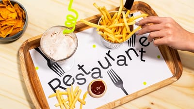 Papel bandeja em uso dentro de uma bandeja de madeira servindo batatas fritas, molho e bebida em um restaurante