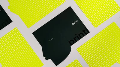 Pasta personalizada da Printi aberta em ângulo, exibindo o exterior preto com logotipo branco e o interior com bolsa para documentos. Ao redor, folhas de papel com padrão repetido de logotipos em verde-limão criam uma composição de papelaria corporativa.