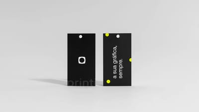 Par de Tag Econômica em papel cartão preto com acabamento fosco e frase "a sua gráfica, sempre" impressa em branco com detalhes em amarelo neon.