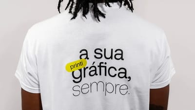 Pessoa vestindo camiseta personalizada branca com estampa “a sua gráfica, sempre” e logotipo Printi.