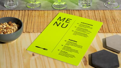 Cardápio de plástico na cor verde-limão em mesa de madeira com vários utensílios de cozinha ao redor