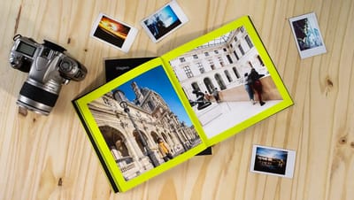 Fotolivro personalizado aberto com fotos de viagem e câmera fotográfica ao lado.