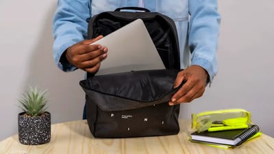 Pessoa colocando notebook em mochila personalizada preta da Printi com compartimento interno acolchoado