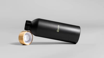Squeeze térmico personalizado preto com tampa de bambu exibido sobre fundo neutro, ideal como brinde corporativo sustentável.