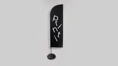 Wind banner personalizado vertical preto com logo Printi montado em base para sinalização externa.